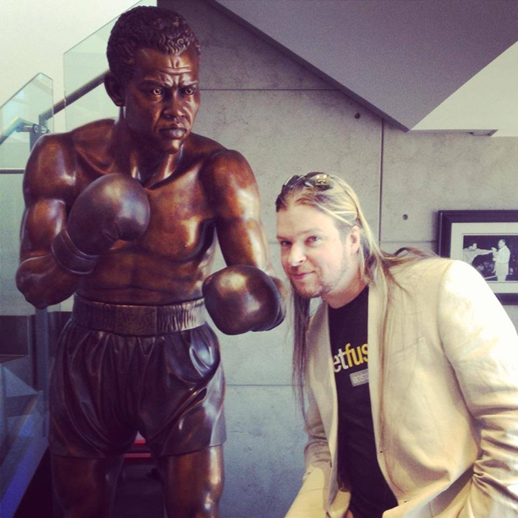 Spencer Collier standing next to a bronze boxing statue.